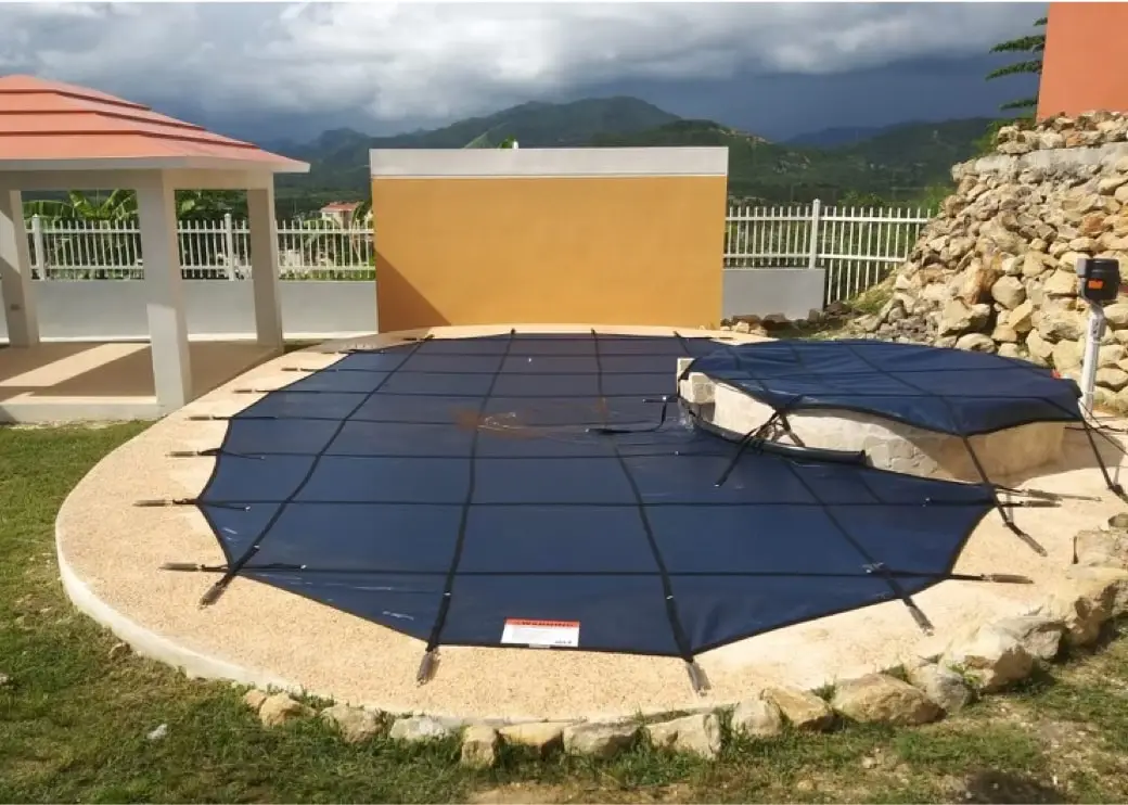 A kidney shaped pool with a blue safety cover.