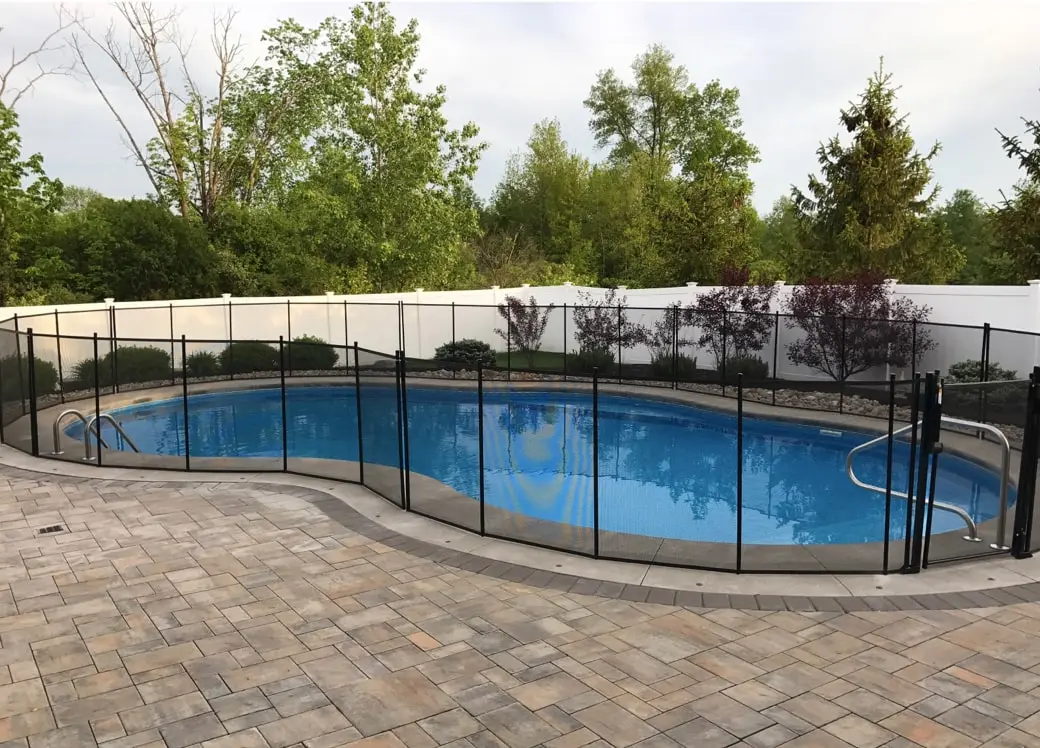 A kidney shaped swimming pool with black fencing.