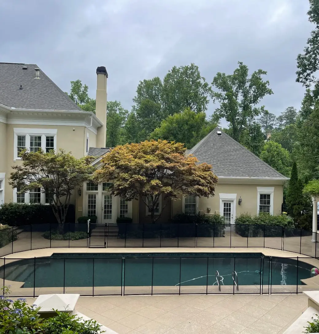 A Roman swimming pool surrounded by black pool fences with a beautiful house in Atlanta.
